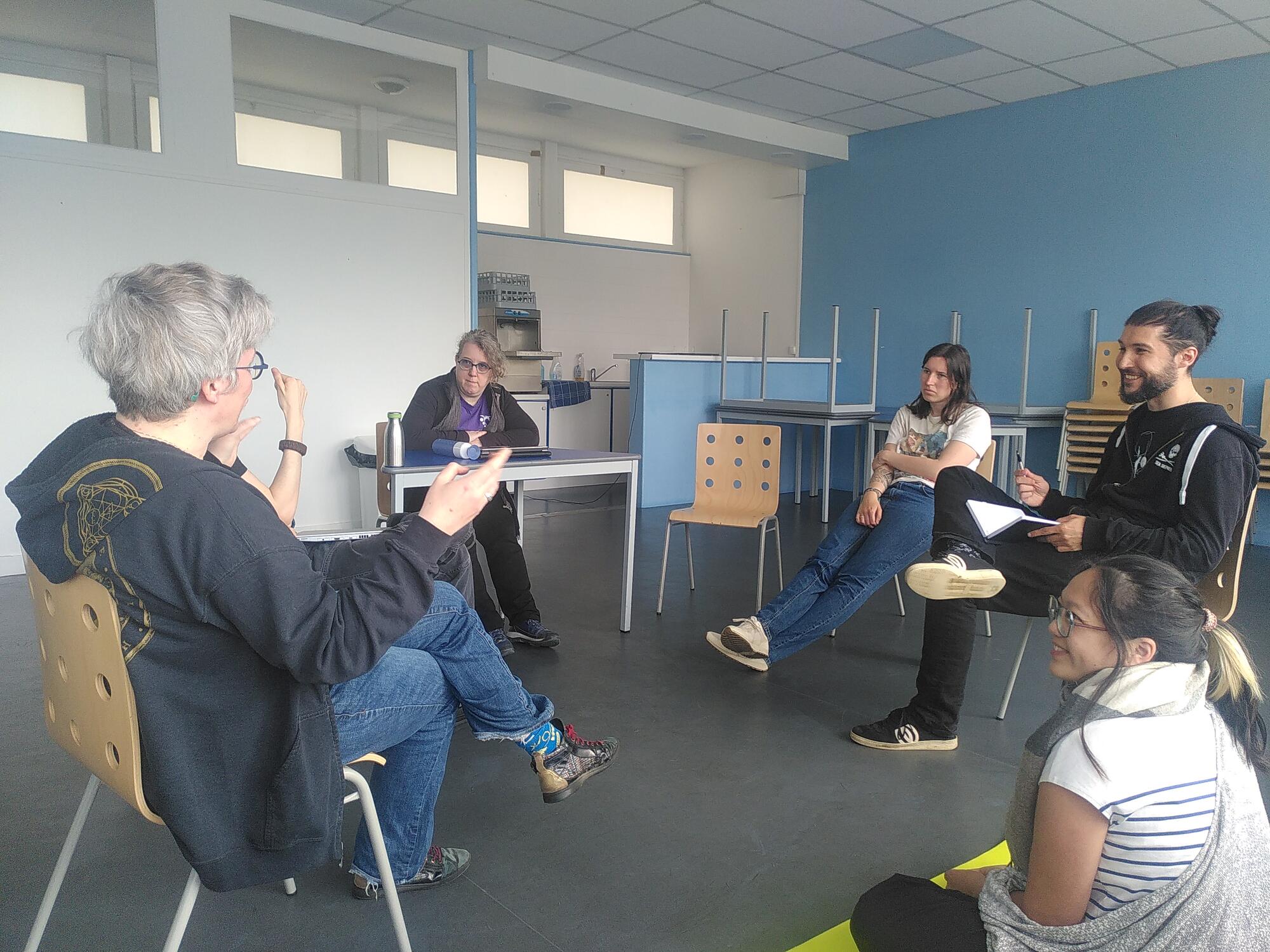 5 personnes assises en cercle et discutant